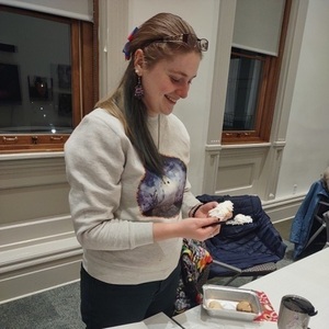Photo of a smiling student frosting a cookie with white frosting.